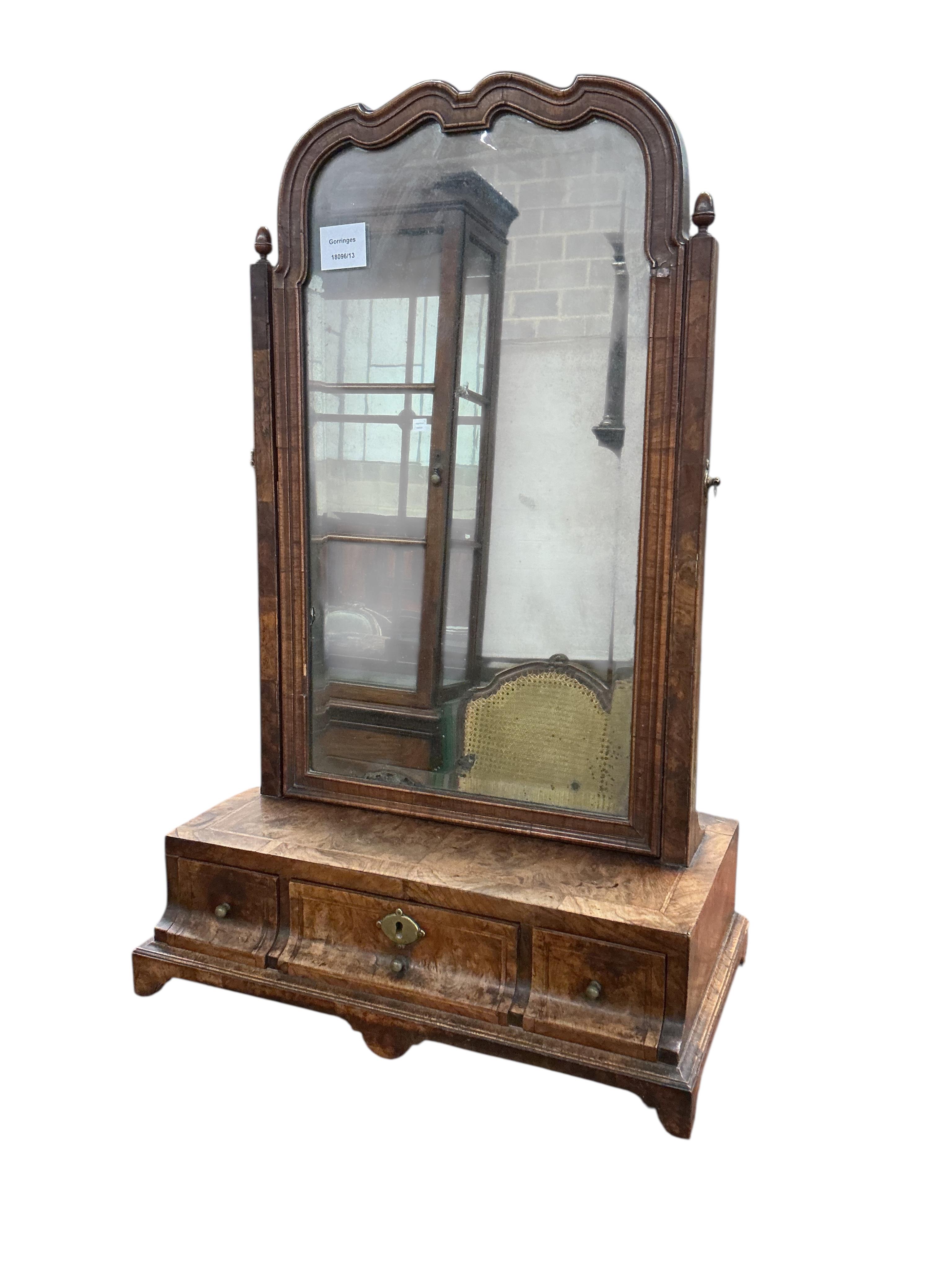 An early 18th century feather banded walnut toilet mirror, with three base drawers, width 44cm, depth 24cm, height 68cm